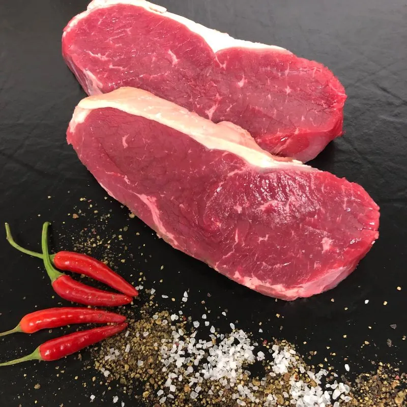 Zwei rohe Entrecôtes mit Salz, Pfeffer und Chili
