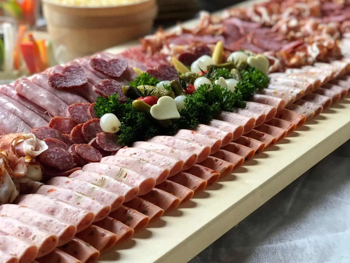 Lange Fleischplatte mit Schinken, Salami, Aufschnitt und Gemüse-Bouquet