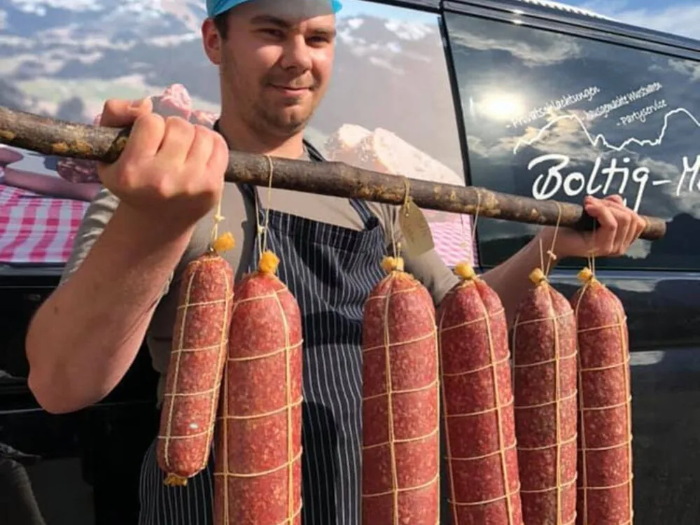 Hans Krebs mit einer Stange Salami vor dem Lieferwagen